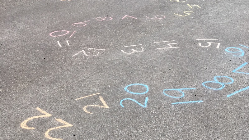 Numbers written in sidewalk chalk in a curvy path