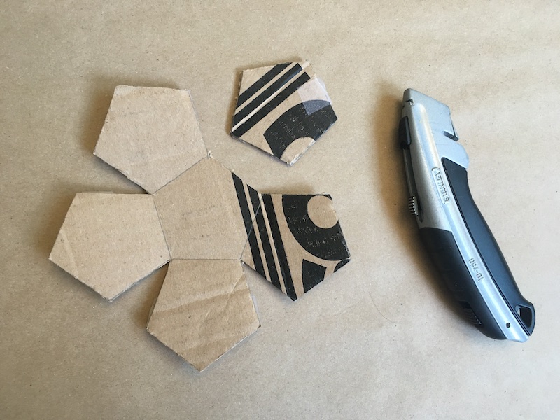 One pentagon cut from a cardboard cutout of six pentagons