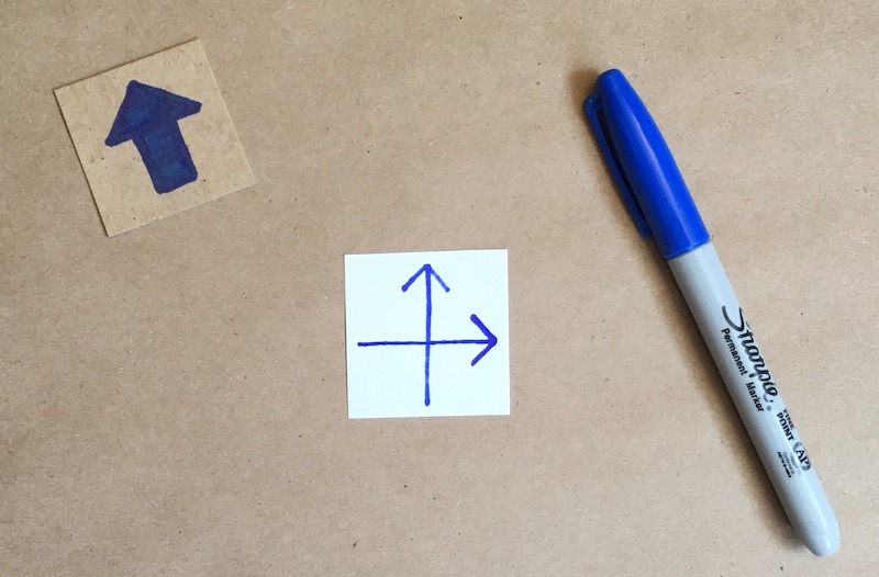 An arrow drawn on the back of the square of paper