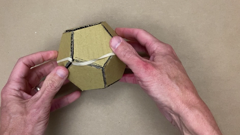 Cardboard dodecahedron with a rubber band around it