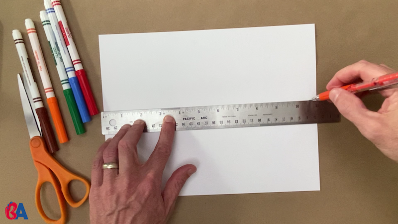 Tracing a line across the center of a paper with a ruler
