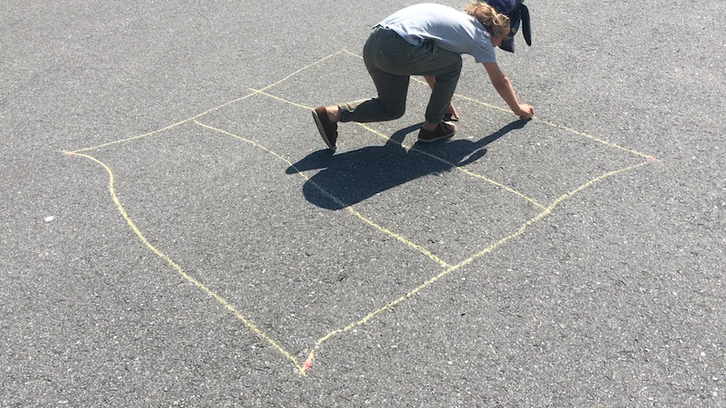 A kid drawing a grid with sidewalk chalk