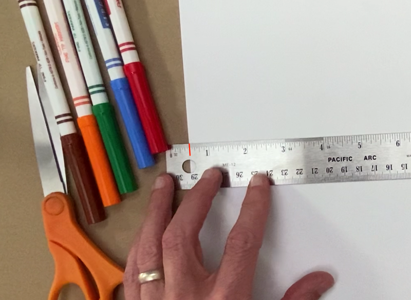 A ruler lined up with the edge of a paper at the half inch mark