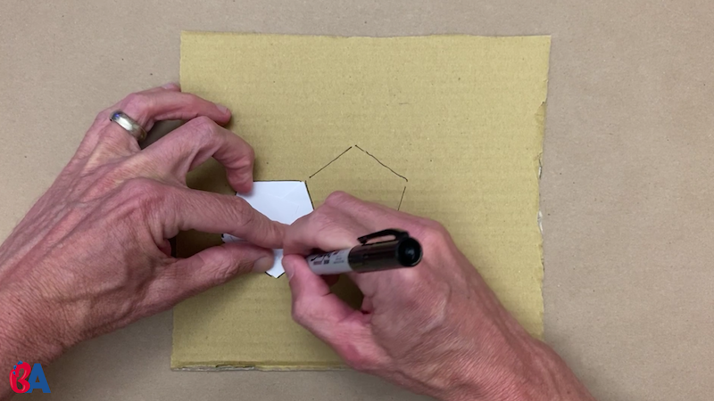 Tracing the paper pentagon onto cardboard